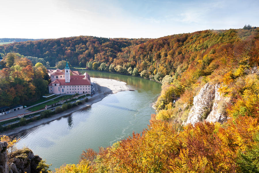 Weltenburg monastery and Donaudurchbruch at the Danube river in Bavaria, Germany surrounded by orange autumn colored trees