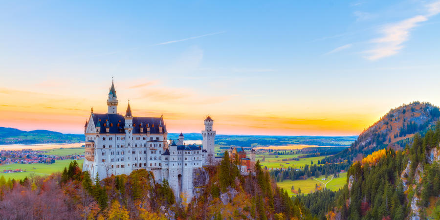 Neuschwanstein, Lovely Autumn Landscape Panorama Picture of the fairy tale castle near Munich in Bavaria, Germany with colorful trees in the morning hours