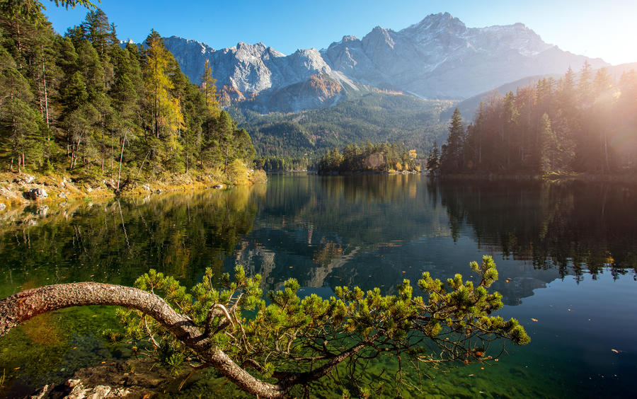 Awesome alpine highlands in sunny day. Nature Landscape. The Eibsee Lake in front of the Zugspitze under sunlight reflected in water. Majestic Autumn Scenery.  Eibsee, Bavaria Germany. Retro Style