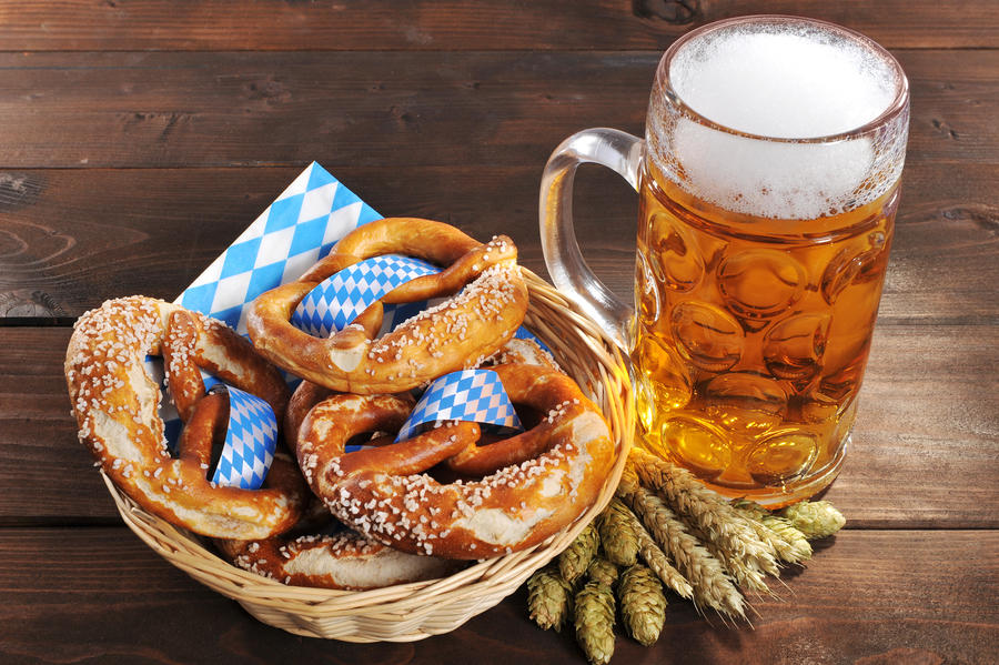 original bavarian Oktoberfest salted soft pretzels in a basket with beer from Germany on wooden board