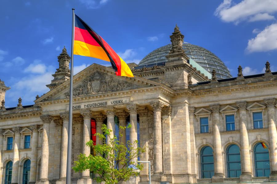 The Reichstag building in Berlin. Flag of the Federal Republic of Germany is waving in front of the national german parliament.
