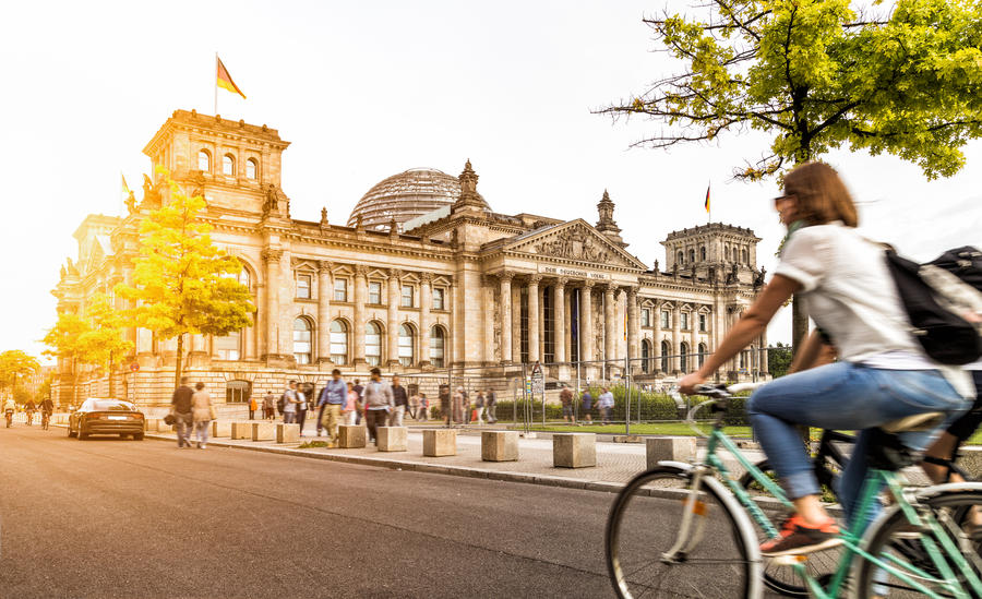 Urban city life with famous Reichstag building in the background in beautiful golden evening light at sunset in summer with retro vintage Instagram style pastel toned filter effect, Berlin, Germany