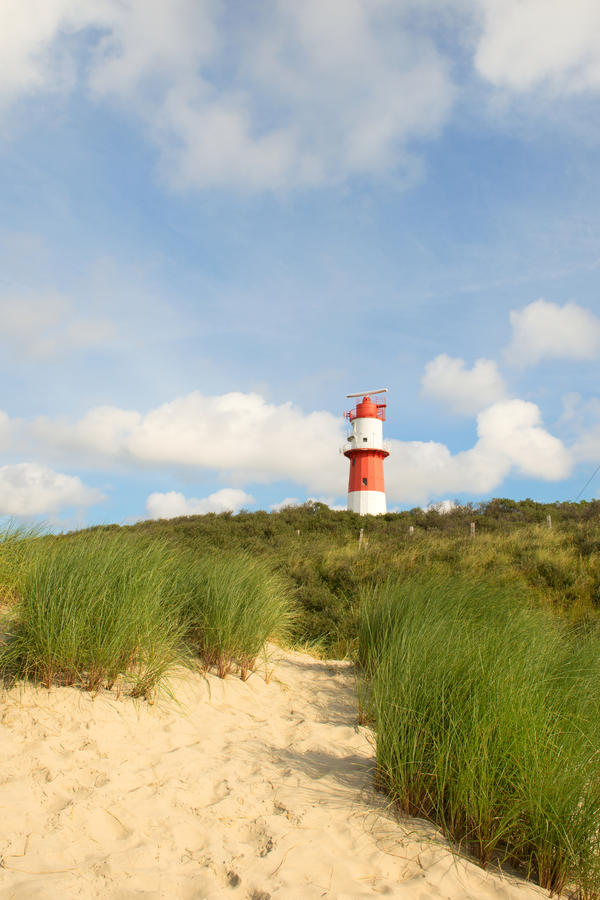 Red and white Lighthouse in landscape with dunes at Borkum