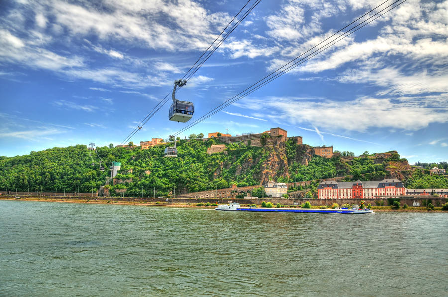 Beautiful HDR image of Fortress Ehrenbreitstein on the mountain in Koblenz over the Rhine river with cable cars moving through mountains.