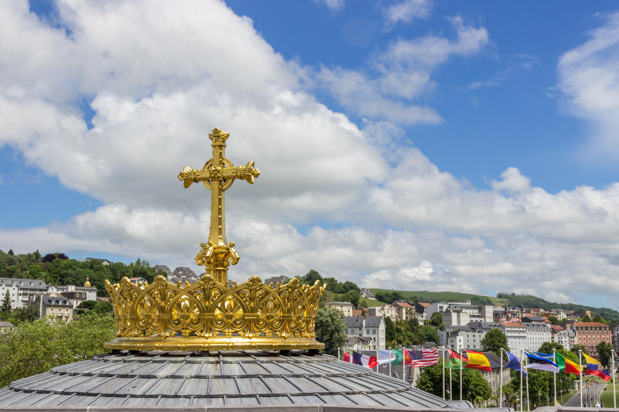 Golden cross and crown against the beautiful sky in Lourdes, France, Hautes Pyrenees. Basilica of our Lady of the Rosary