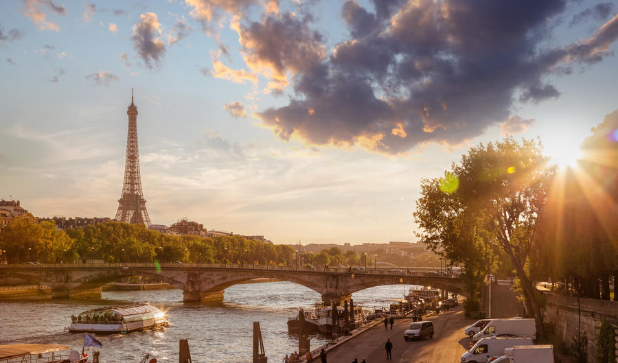 Eiffel Tower against colorful sunset with boat on Seine in Paris, France