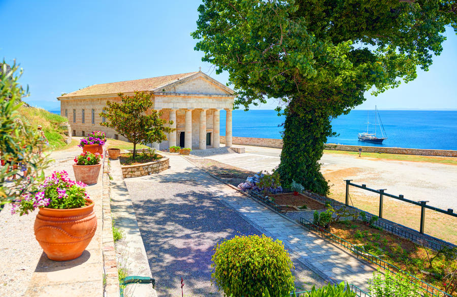 View on classical Greek temple Saint George church architecture of Greece Corfu island capital Kerkyra. Classic yacht. Greece holidays vacation touristic tours. Old Venetian Fortress sightseeing tour