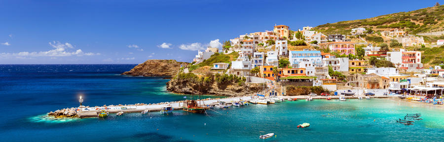 Crete, Greece. Harbor with marine vessels, boats and lighthouse. View from cliff on Bay with beach and architecture Bali - vacation destination resort with clear ocean water. Rethymno, Crete, Greece