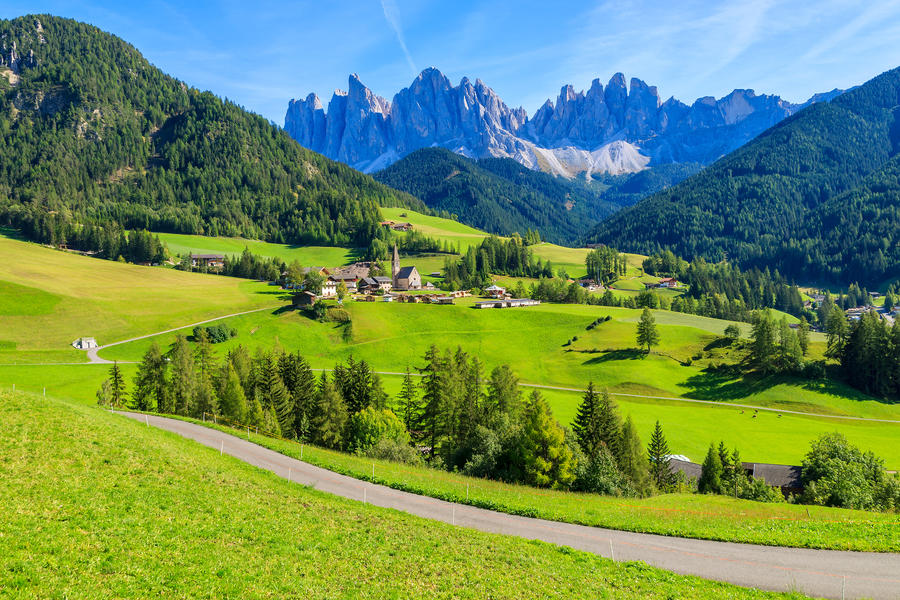 Rural road in green alpine valley with view of Santa Maddalena village church, Val di Funes, Dolomiti Mountains, Italy