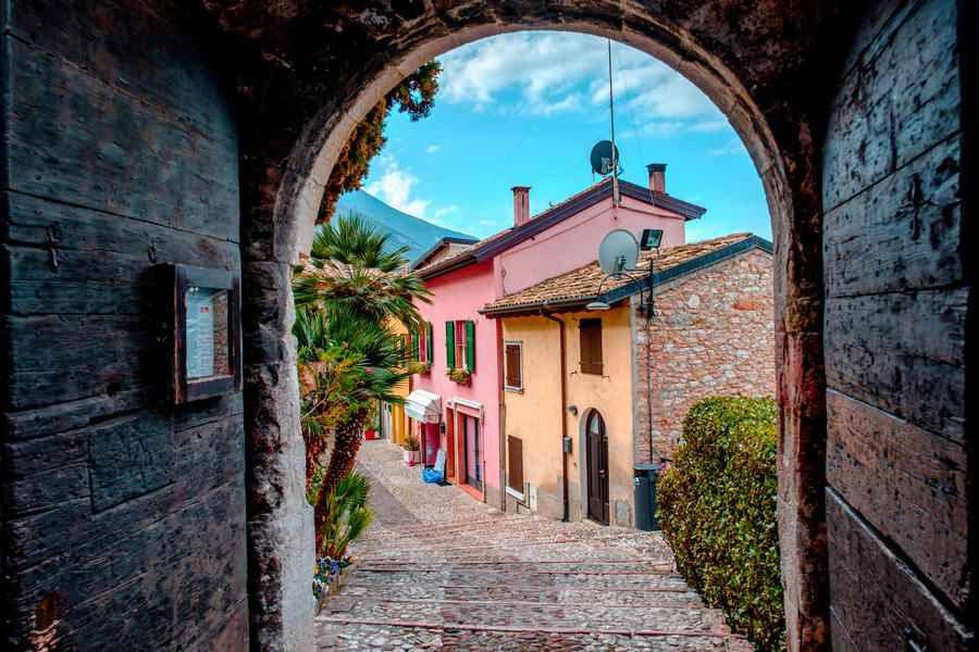 View of the street with colored houses from a dark arch. The city of Malcesine. Italy.