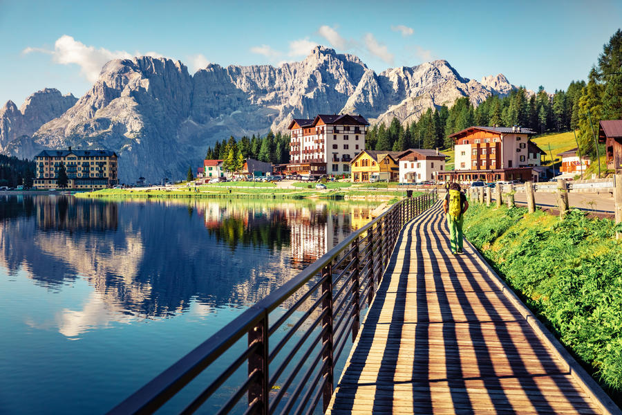 Tourist walking on the pier on Misurina lake. Sunny morning scene of Misurina resort, National Park Tre Cime di Lavaredo, Location Auronzo, Dolomiti Alps, South Tyrol, Province of Belluno, Italy, Euro
