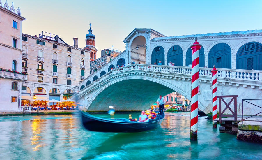 The Rialto Bridge in Venice in the evening, Italy. Long exposition - Gondola and people in the motion blur