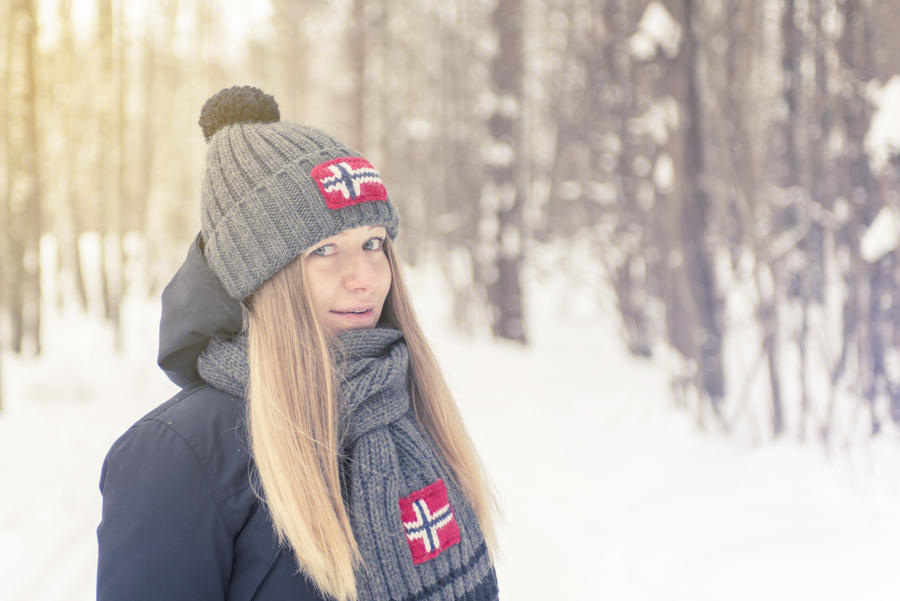 The young girl in the winter cold wood in a cap and a scarf with a flag. Tinted photo