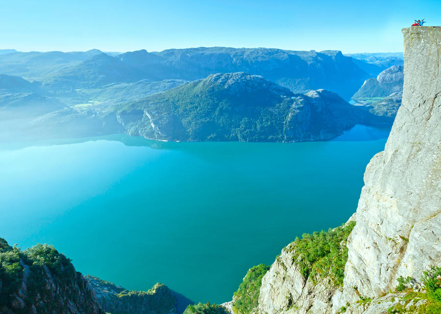 Happy family on top of Preikestolen massive cliff (Norway, Lysefjorden summer view).