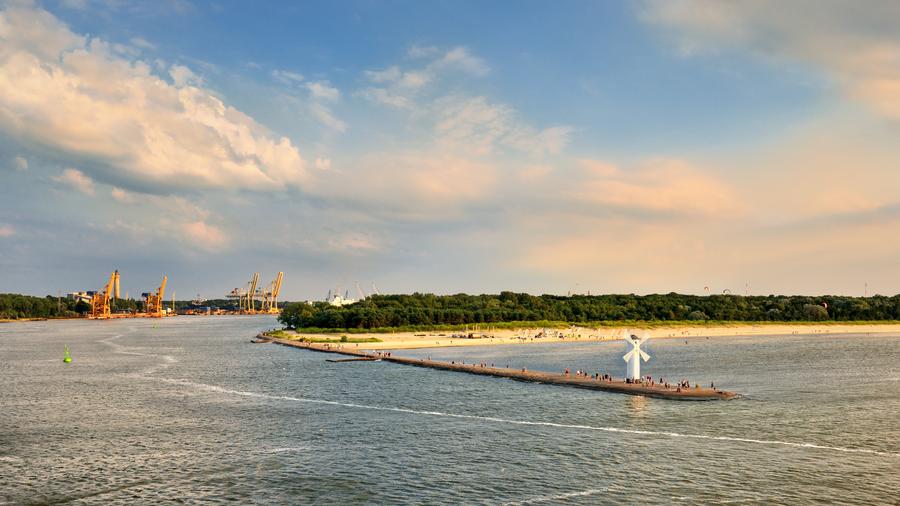 White old lighthouse in Swinoujscie, stone pier and wavy sea, Poland