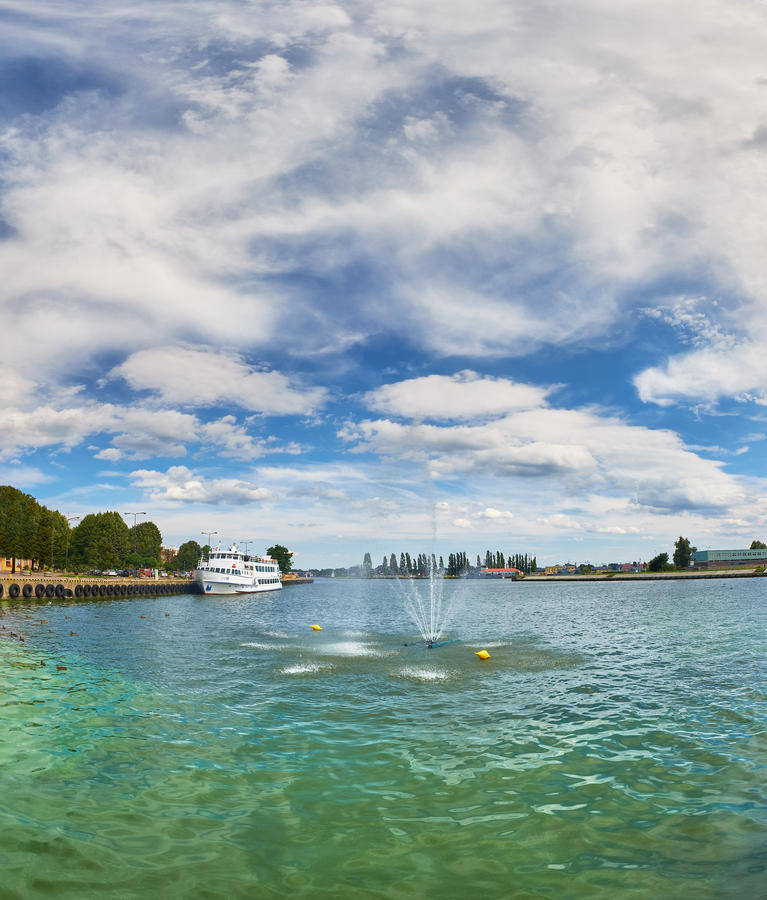 Panoramic image of a fountain in Swina river and river promenade in Swinoujscie, Poland