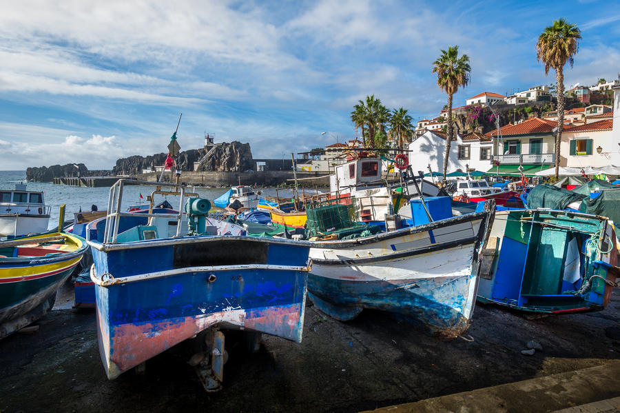Close view of aged and abandoned fishing boats laying on the shore. Camara de Lobos marina, Madeira, Portugal.