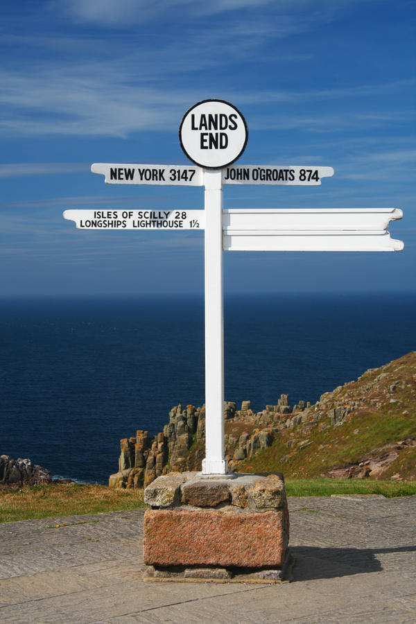white Land's end directional sign over sea and cliffs background