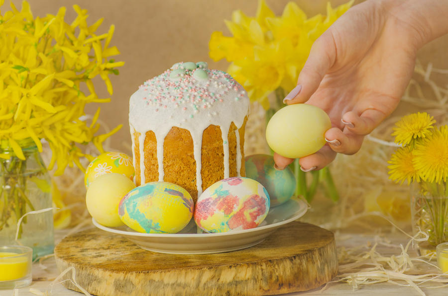 Table decorating for  holiday.   Easter eggs and Easter decoration on the wooden background. Female hand with Easter eggs. Hands holding painted Easter egg