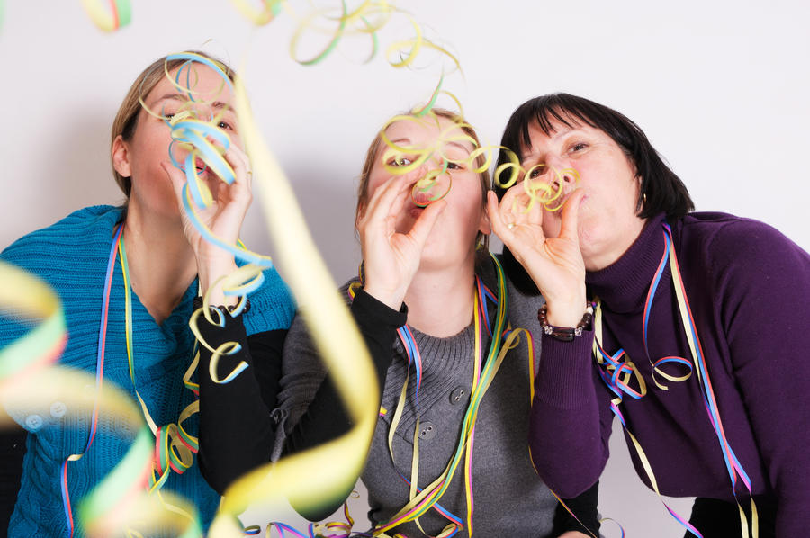 Two young women and one senior woman celebrating New year&#39;s eve. Shot taken in front of white background