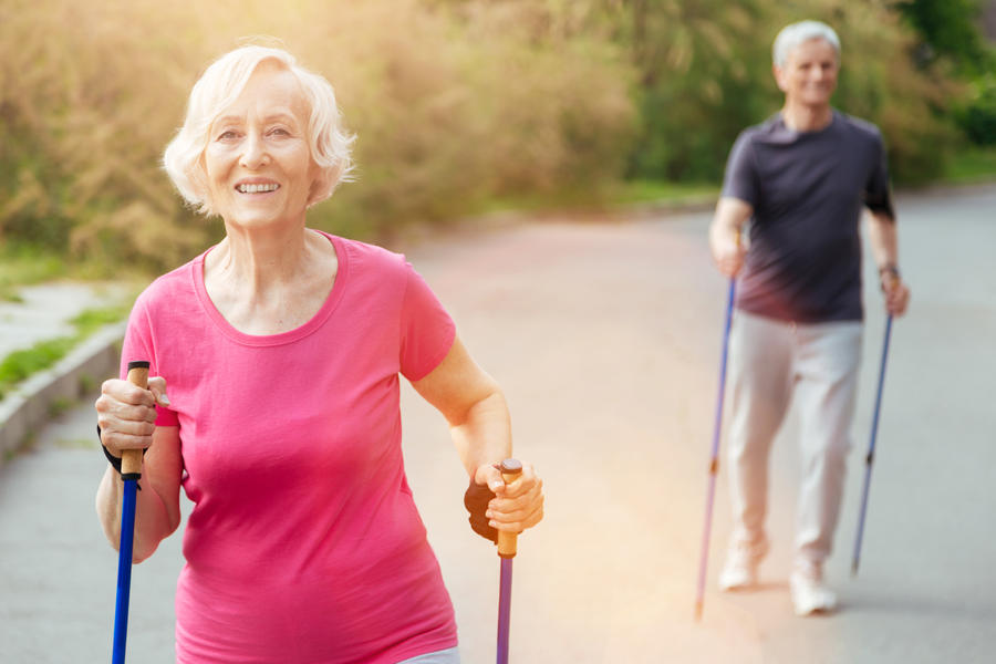 Positive emotions. Happy delighted senior woman practicing Nordic walking and smiling while being in a good mood