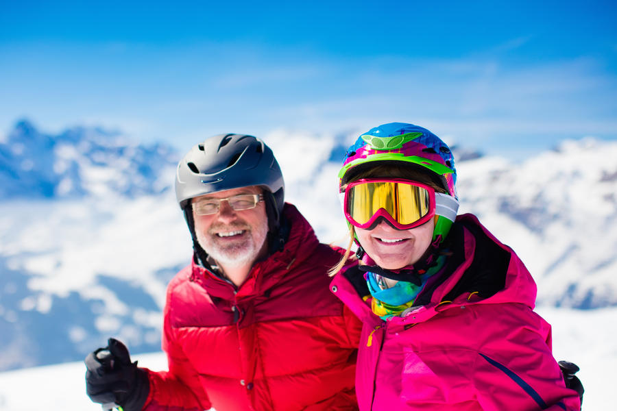 Happy mature couple skiing in the Alps mountains. Senior man and woman enjoying ski vacation in alpine resort. Active retirement. Healthy winter sport for every age.