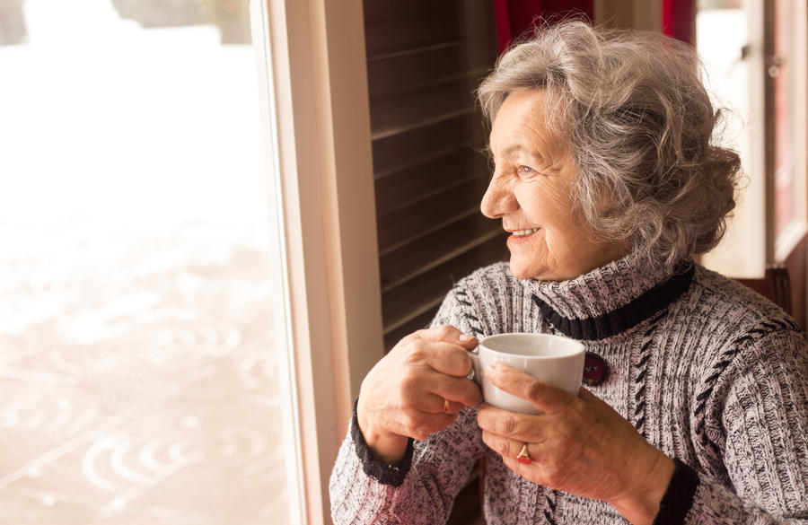 Senior woman drinking coffee and looking through window