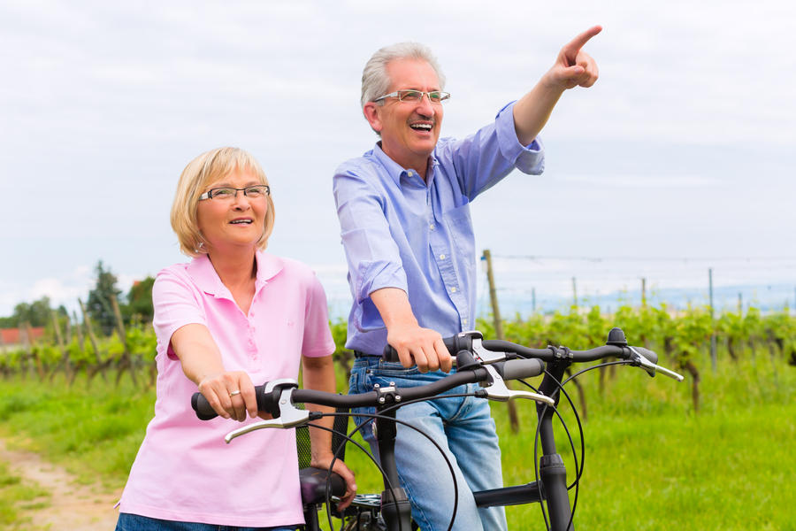 Senior Man and woman exercising with bicycles outdoors, they are a couple