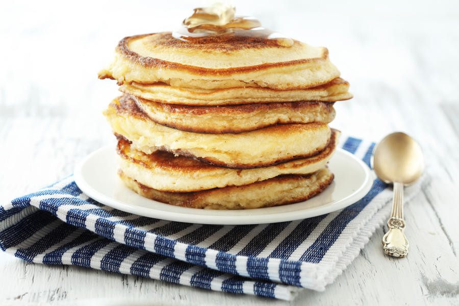 Stack of pancakes with honey on vintage white wooden background