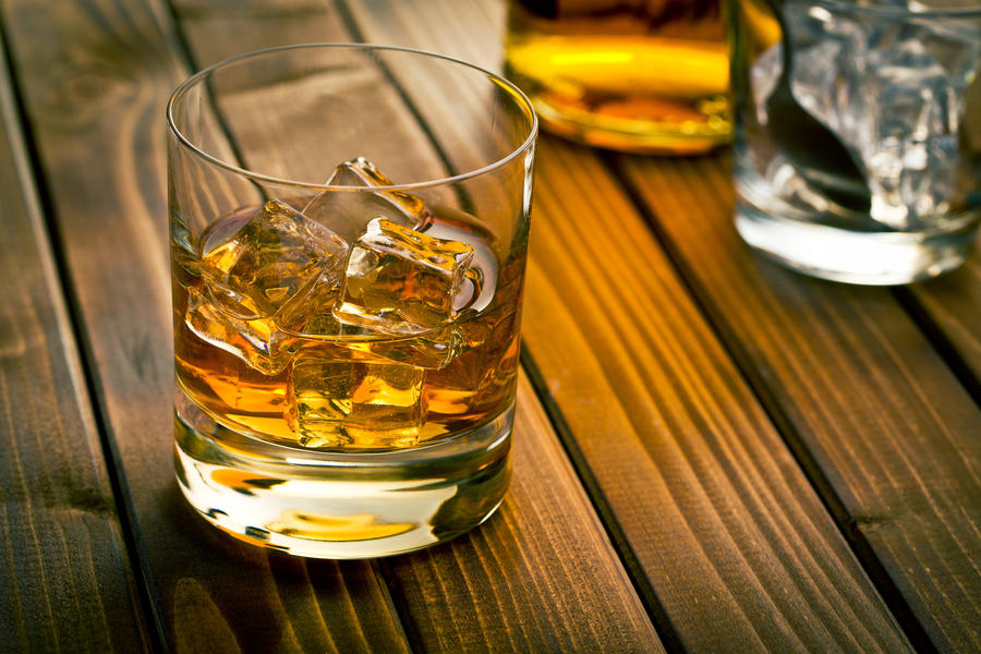 whiskey in glass with ice on wooden table