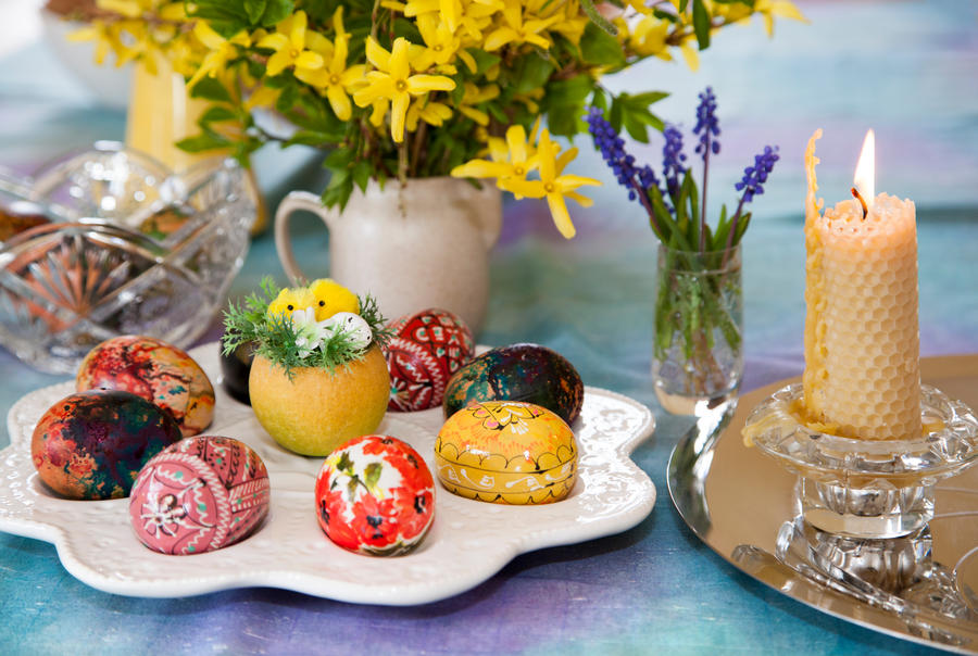 The close view of a candle made of bee honey and colorful eggs as Easter table decoration (Lithuania).