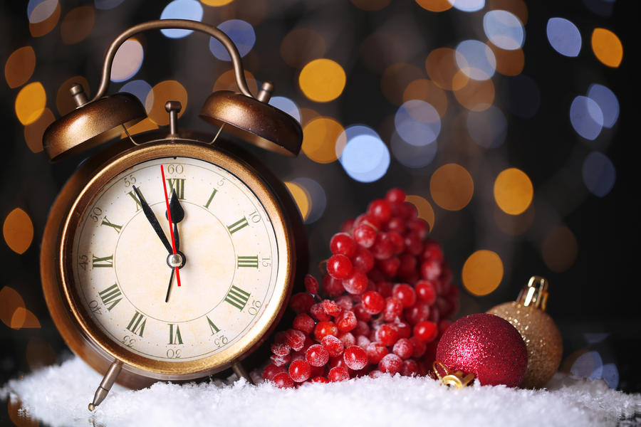 Alarm clock with snow and Christmas decorations on table on bright background