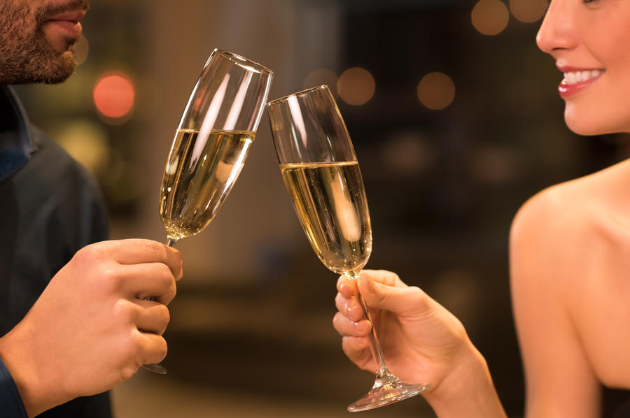 Couple toasting champagne glasses in a luxury restaurant. Couple enjoying meal and drinks in a restaurant. Young loving couple celebrating their anniversary, new year.