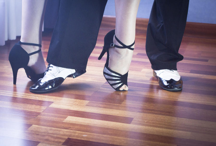 Male and female ballroom, standard, sport dance, latin and salsa couple dancers feet and shoes in dance academy school rehearsal room dancing salsa.