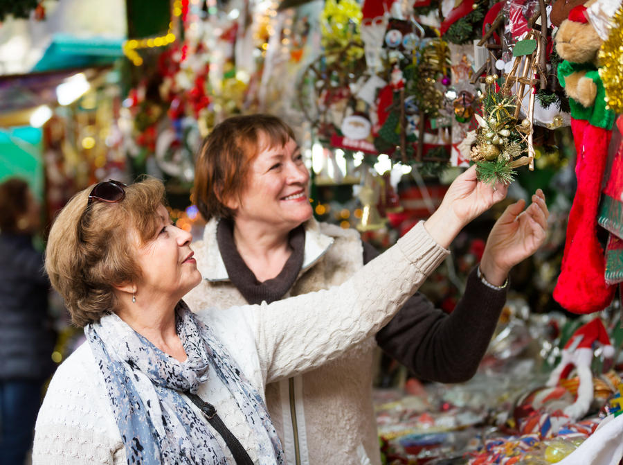 Cheerful female pensioners buying X-mas decorations and souvenirs at the fair
