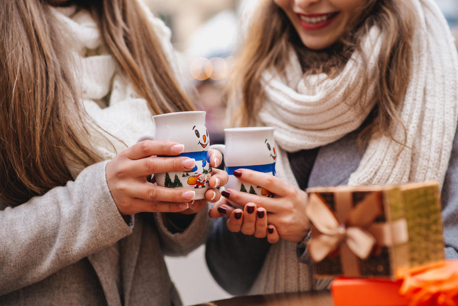 two female best friends drinking mulled wine on christmas and new years decorations outdoor