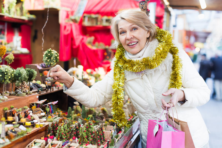 Mature woman choosing decorations at Christmas market  and walking