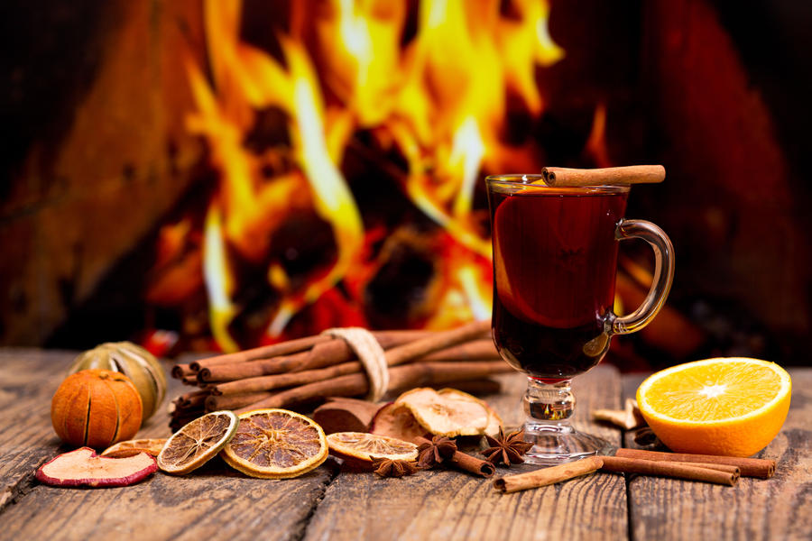 Glass of christmas mulled wine on wooden table against fireplace