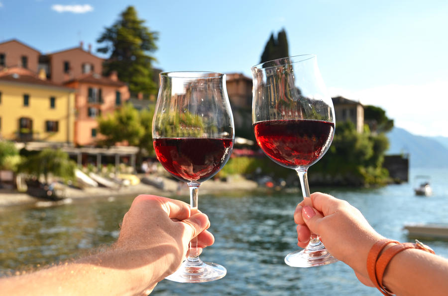 Two wineglasses in the hands. Varenna town at the lake Como, Italy