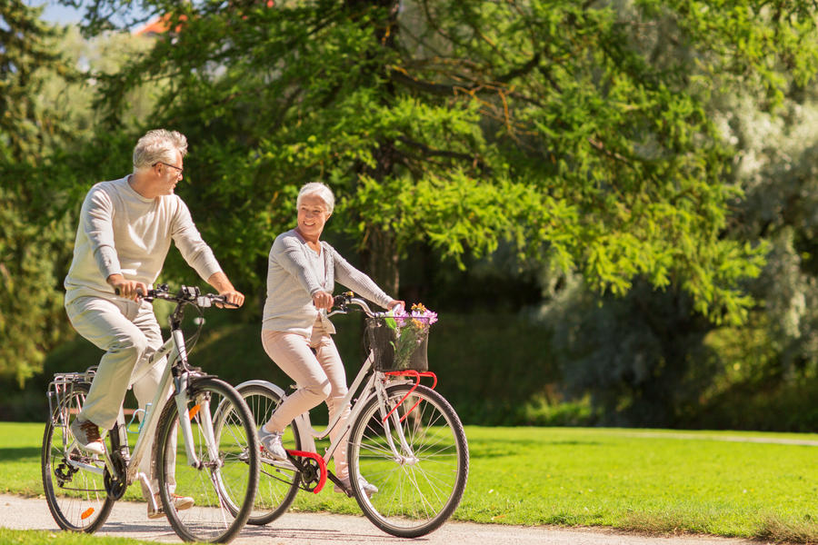 active old age, people and lifestyle concept - happy senior couple riding bicycles at summer park
