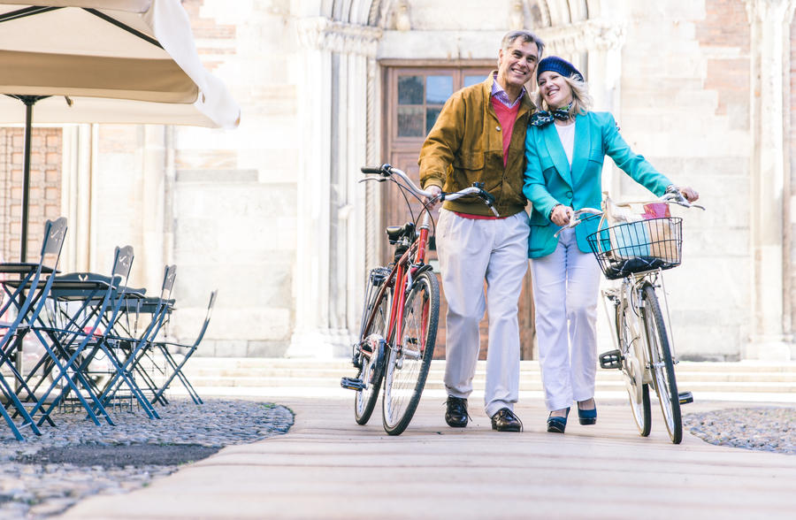 Senior couple walking with their bicycle in the city center
