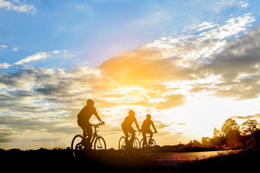 Men ride a bicycle at sun set .The image of cyclists in motion on the background in the evening.