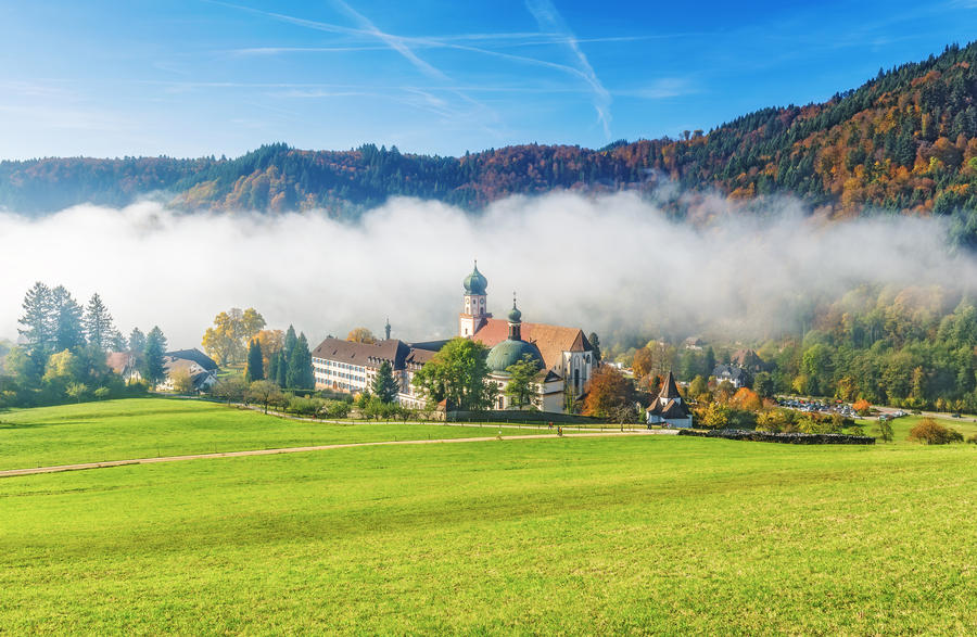Scenic foggy mountain landscape with an old monastery in Black Forest, Germany. Colorful travel background.