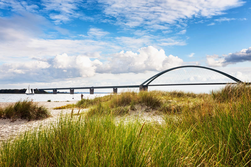 Fehmarn sound bridge. Late summer landscape with beach, dune grass and cloudy sky. Vacation background. Baltic sea coast, Germany, travel destination
