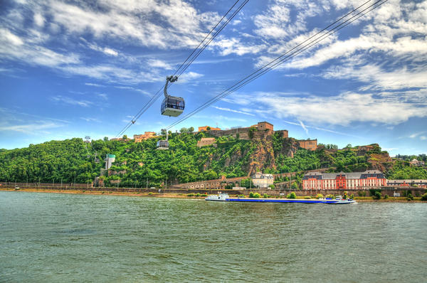 Beautiful HDR image of Fortress Ehrenbreitstein on the mountain in Koblenz over the Rhine river with cable cars moving through mountains.