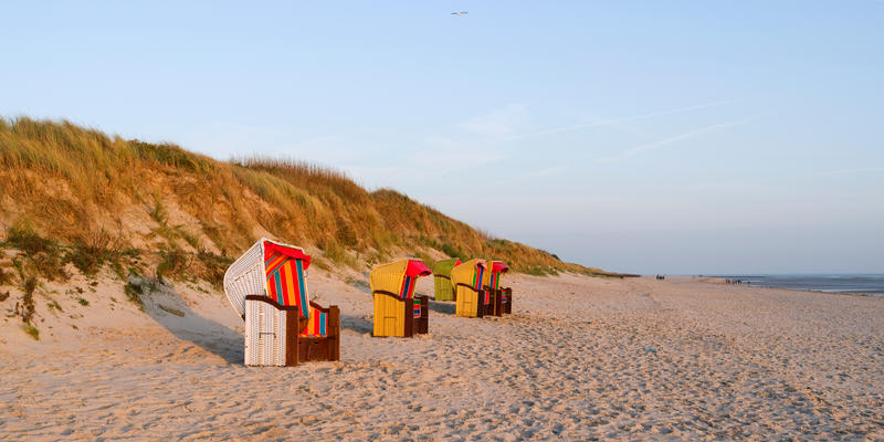 Foehr / Germany: Colorful empty hooded beach-chairs at Goting beach on the south coast of the Frisian island in the deep November afternoon sun