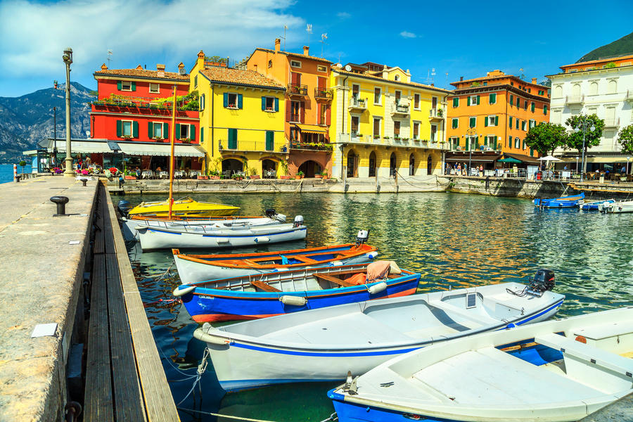 Amazing summer landscape, fishing boats and typical colorful Italian buildings in spectacular harbor, Malcesine tourist resort, lake Garda, Veneto region, Italy, Europe