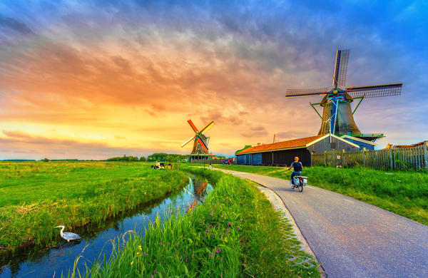 Traditional village with dutch windmills and river at sunset, Holland, Netherlands.