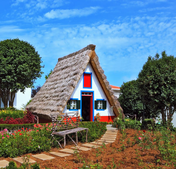 Traditional rural landscape. The village - Museum of the Portuguese island of Madeira. The little white house with a triangular thatched roof and a red door.