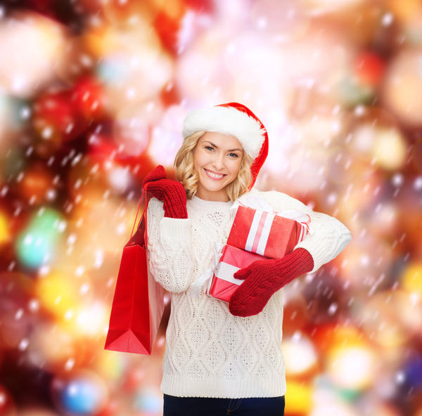 shopping, sale, gifts, christmas, x-mas concept - smiling woman in santa helper hat with shopping bags and gift boxes